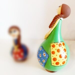 Μια νεροκολοκύθα μεταμορφώνεται σε κούκλα! Μια νεροκολοκύθα έμεινε πολλές ώρες κάτω από τον ήλιο για να στεγνώσει. Δυο χέρια έπλασαν το κεφάλι, τη μύτη, τα μάτια, τα χέρια και τα στολίδια της και τα πρόσθεσε πάνω στη νεροκολοκύθα και της έβαλε μια βάση για να στέκεται όρθια και καμαρωτή πάνω στο ράφι, στο τραπέζι, στο τζάκι, στη βιτρίνα και όπου αλλού μπορείς να σκεφτείς! Το μόνο που κάνει είναι να σε μαγεύει με την παρουσία της και να διακοσμεί με τον δικό της μοναδικό τρόπο το χώρο σου! Μια νεροκολοκύθα έργο τέχνης, ζωγραφισμένη όλη στο χέρι σε πολλά χρώματα και σχέδια για να διαλέξεις εκείνη που σου αρέσει το περισσότερο! Αν την κουνήσεις ακούς και τα σπόρια της! Κι αν την παρατηρήσεις όλο και κάτι έχει να σου πει με το σκέρτσο και τα μάτια της!